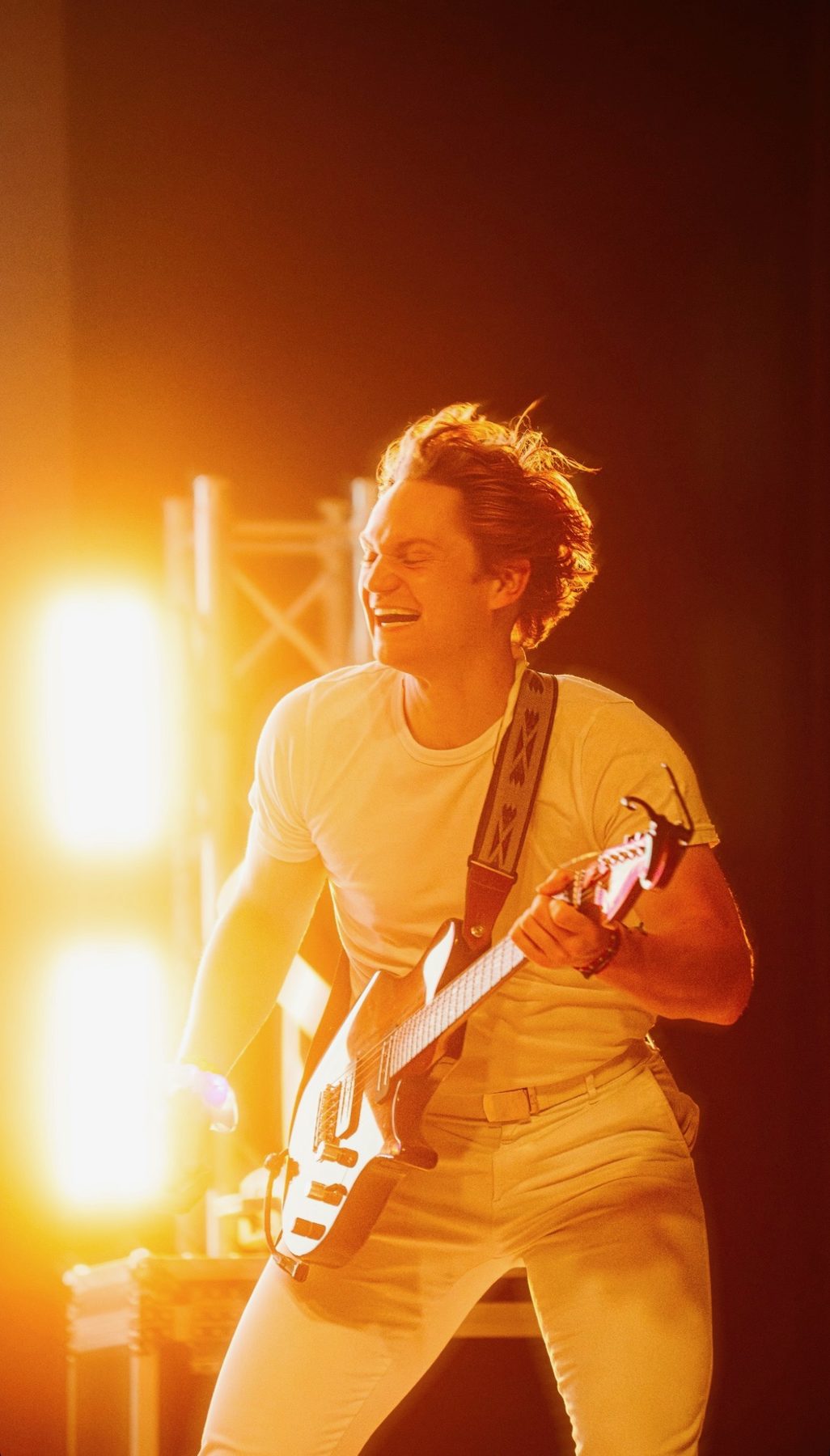 Late Noper playing guitar on stage under warm stage lights