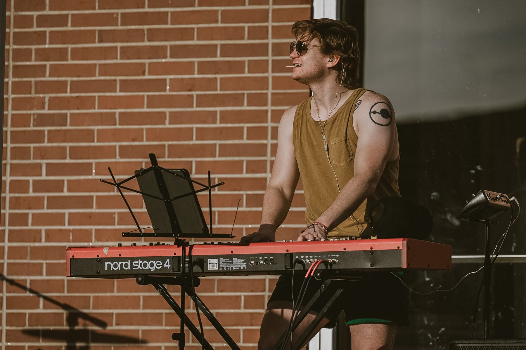 Late Noper performing on a Nord Stage keyboard in front of a brick wall